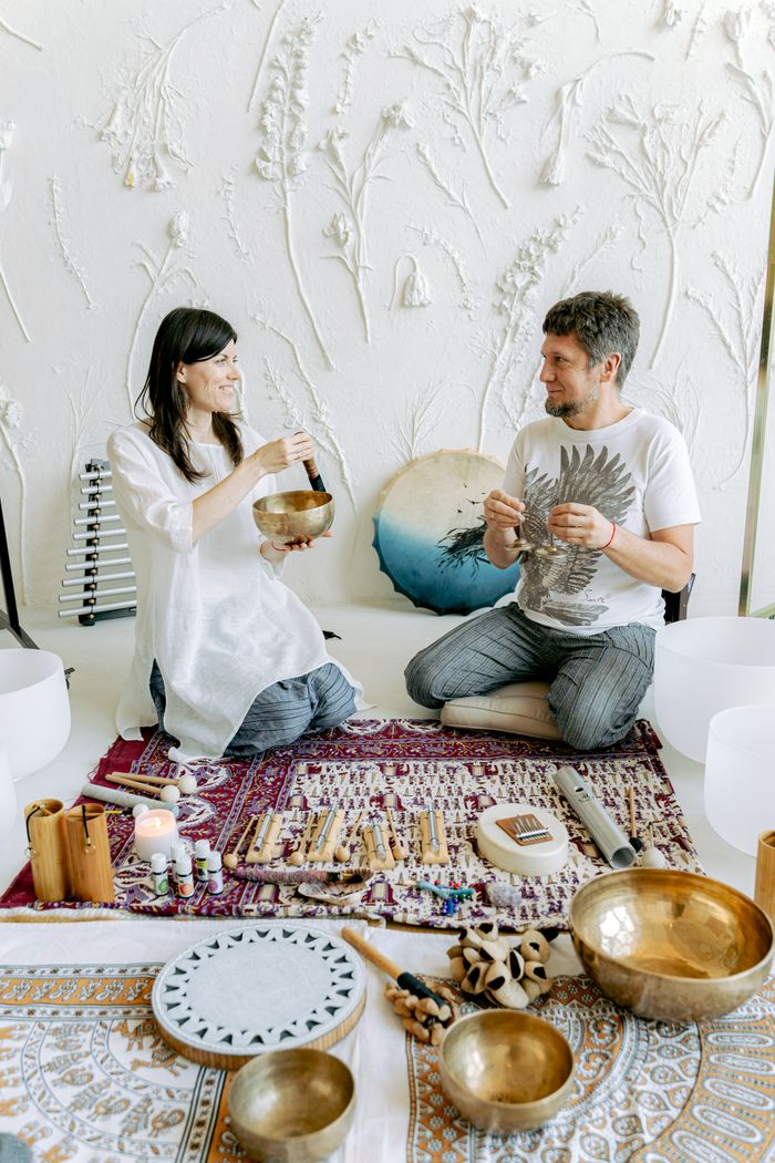 A couple engaging in sound therapy with Tibetan singing bowls indoors.