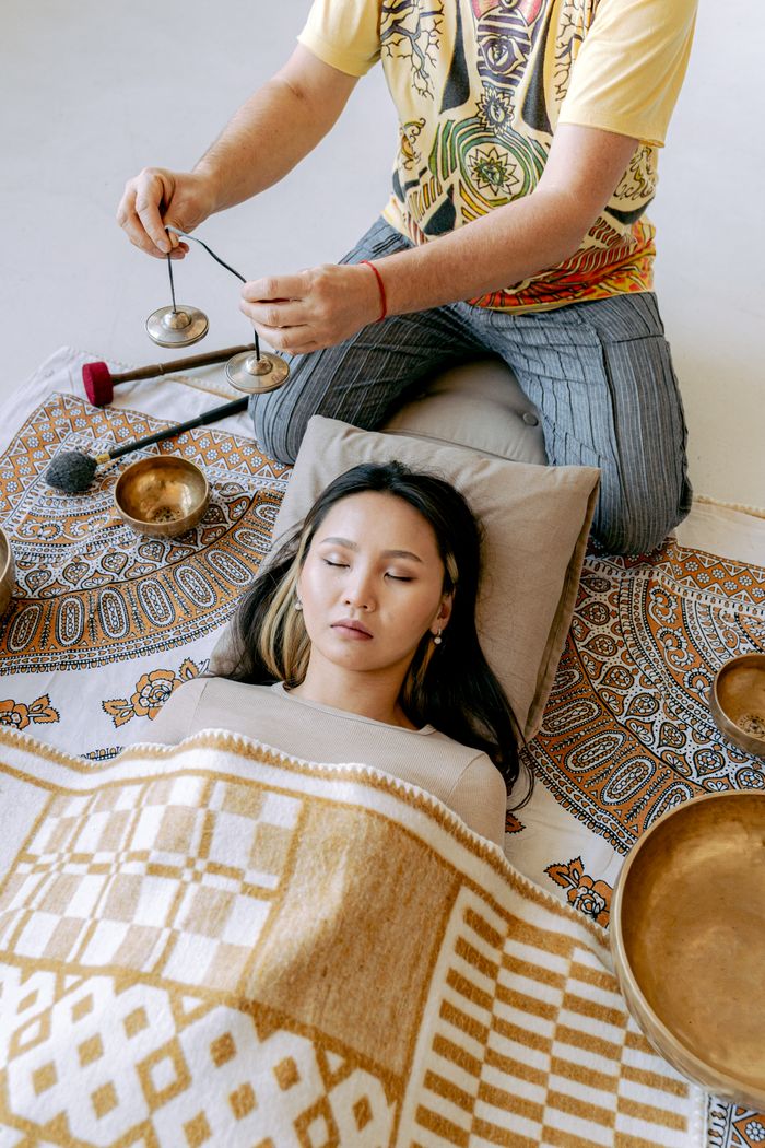 An Asian woman relaxes during a Tibetan sound healing meditation session.